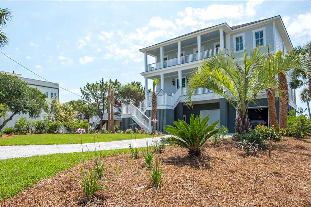 Well maintained lawn and planting beds at a raised coastal home serviced by Priority Landscaping
